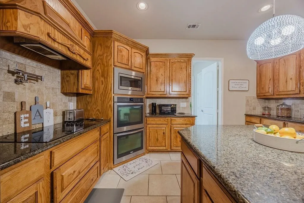 Kitchen with backsplash, granite countertops, and wood finish cabinetry