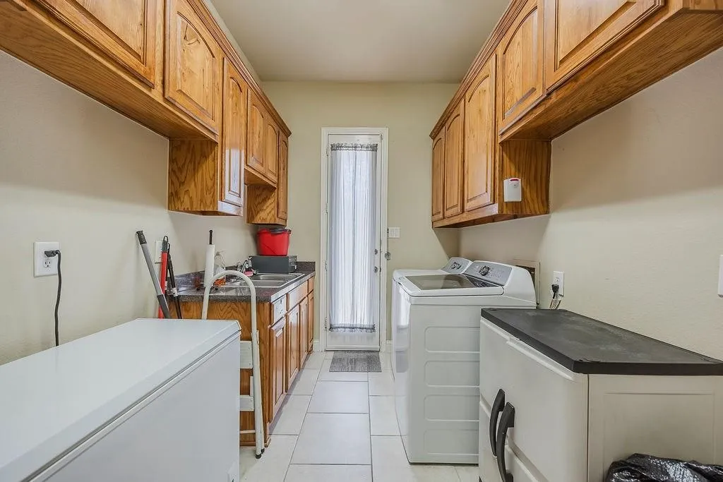 Laundry area with cabinet space, washing machine and dryer, and light tile patterned floors