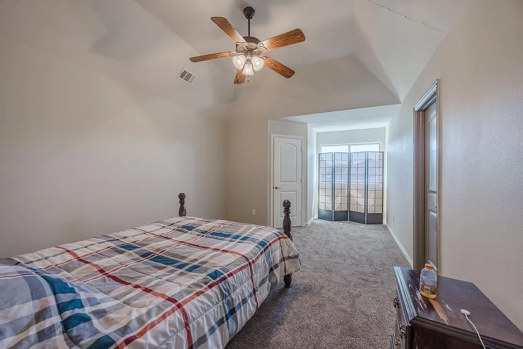 Carpeted bedroom featuring ceiling fan and lofted ceiling