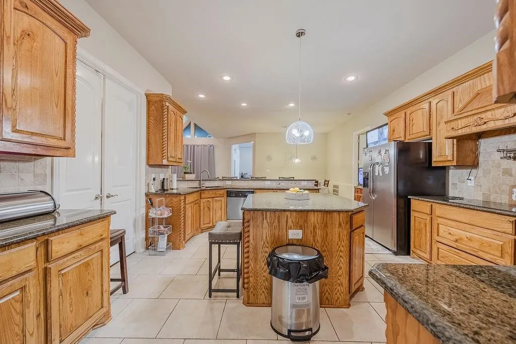 Kitchen featuring tasteful backsplash, a peninsula, granite counters, and a kitchen island