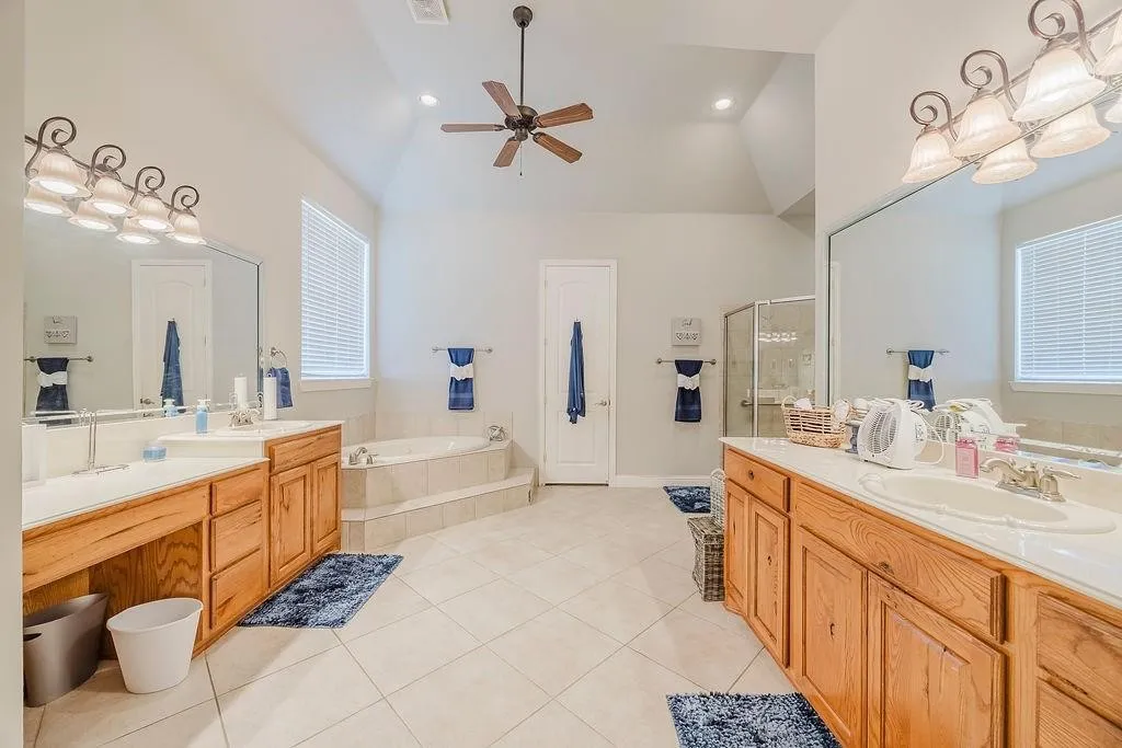 Bathroom with a garden tub, two vanities, a shower stall, light tile patterned floors, and recessed lighting