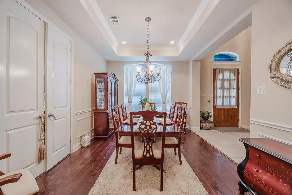 Dining area featuring dark wood-style floors, a tray ceiling, a chandelier, and ornamental molding