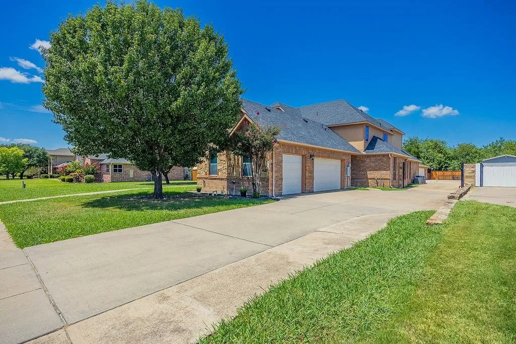 View of front of house featuring a front lawn, concrete driveway, a garage, and brick siding