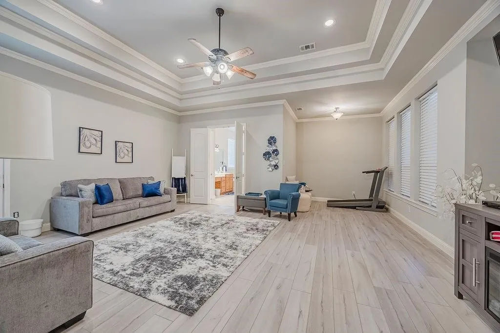 Living area featuring ceiling fan, light wood finished floors, recessed lighting, a tray ceiling, and crown molding