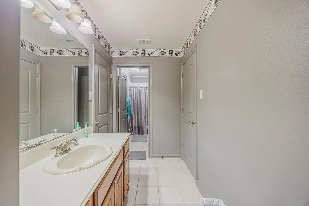 Bathroom featuring vanity, curtained shower, and light tile patterned floors