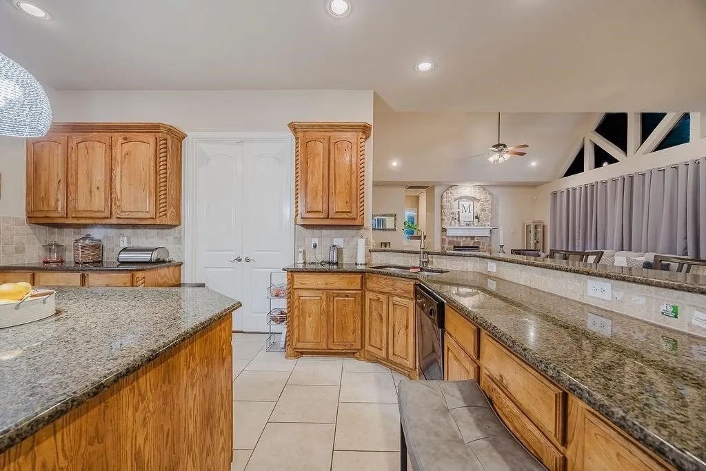Kitchen with granite counters, ceiling fan, wood finish cabinetry, and recessed lighting