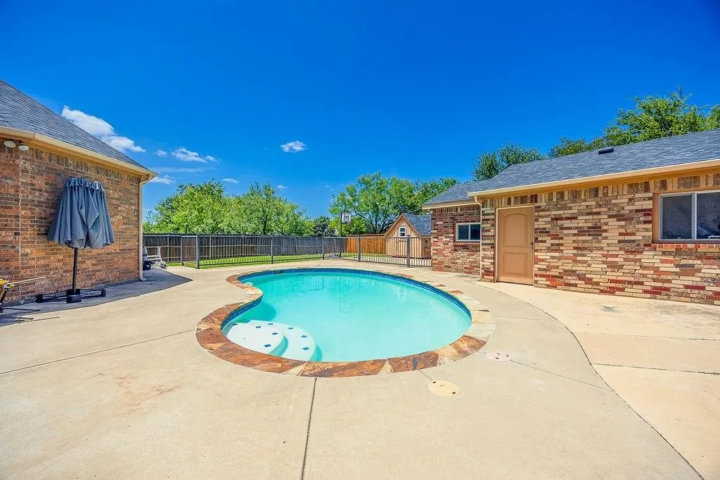 View of swimming pool featuring patio surround and a fenced backyard