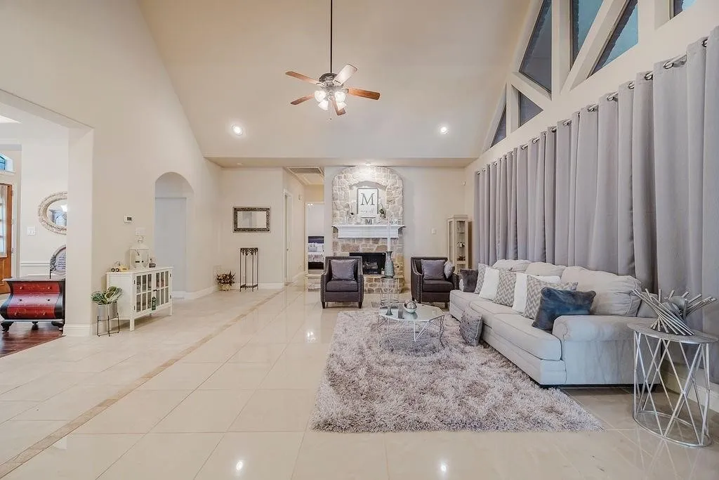 Living room with light tile patterned floors, a ceiling fan, a stone fireplace, recessed lighting, and vaulted ceiling