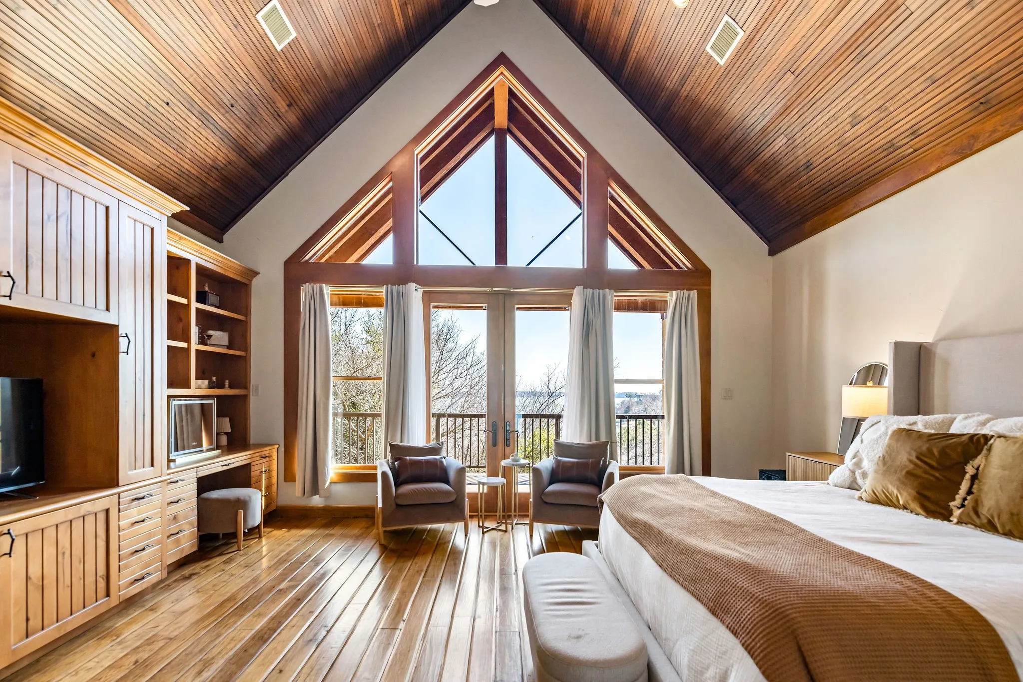 Hill Lodge’s bedroom 1 of 3 features soaring wood ceilings, custom built-ins, and large windows that fill the space with natural light.
