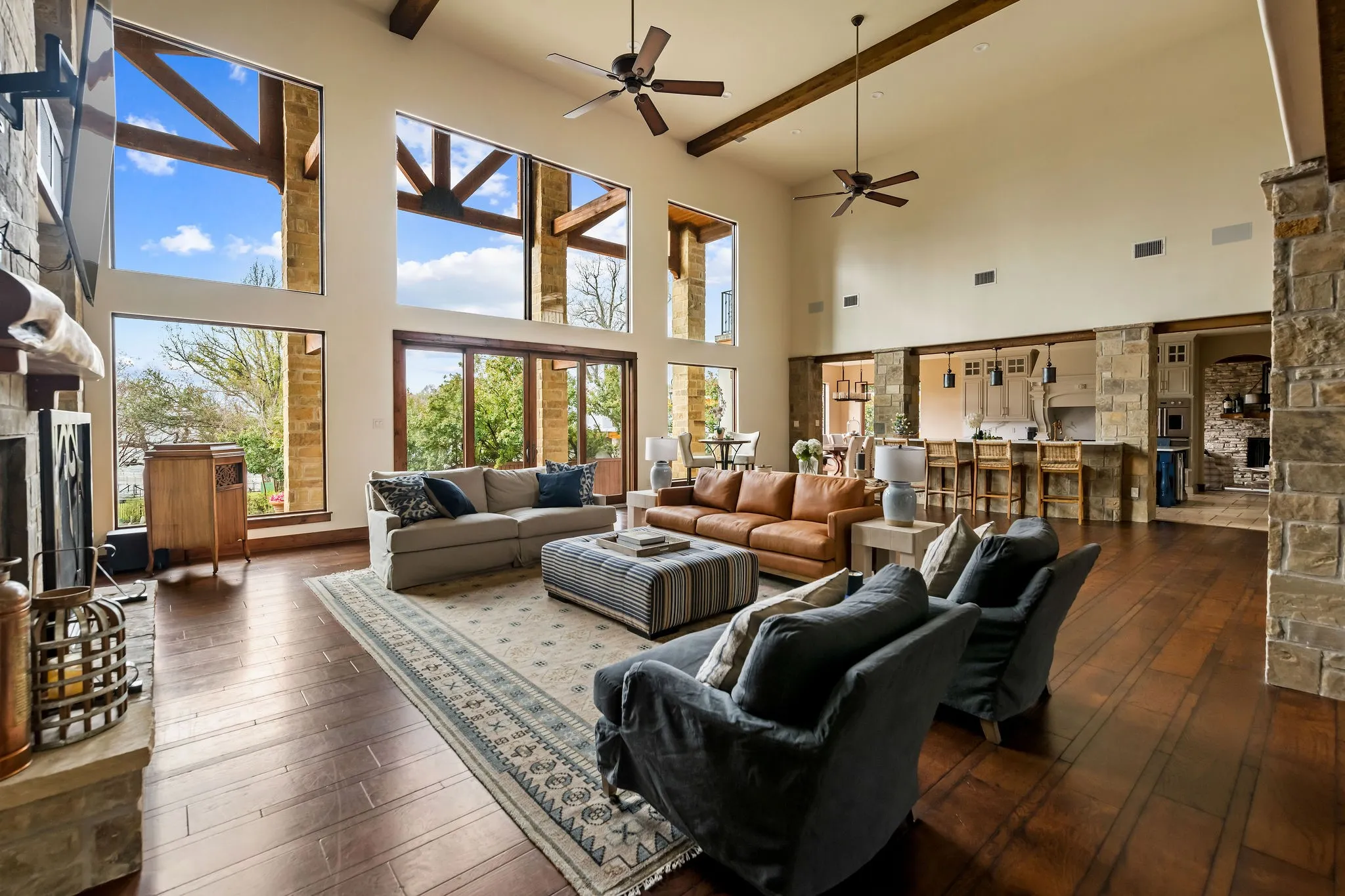 Main residence great room features beamed sky-high ceilings and floor to ceiling windows providing stunning views of the water.