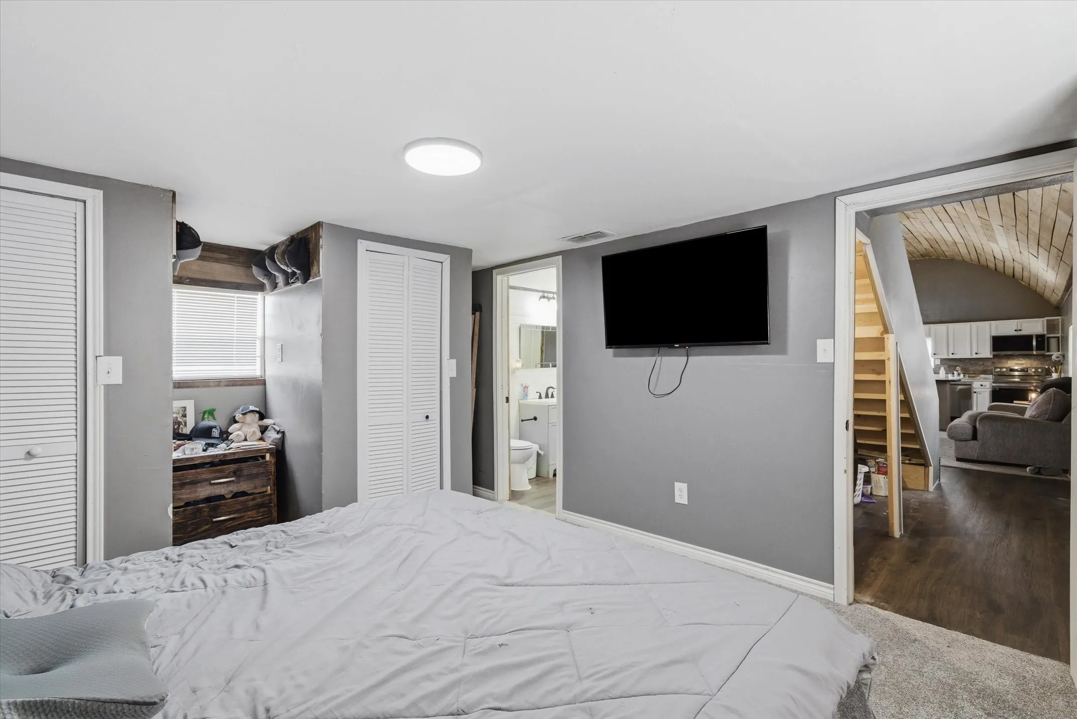 Bedroom featuring two closets, ensuite bath, and carpet floors