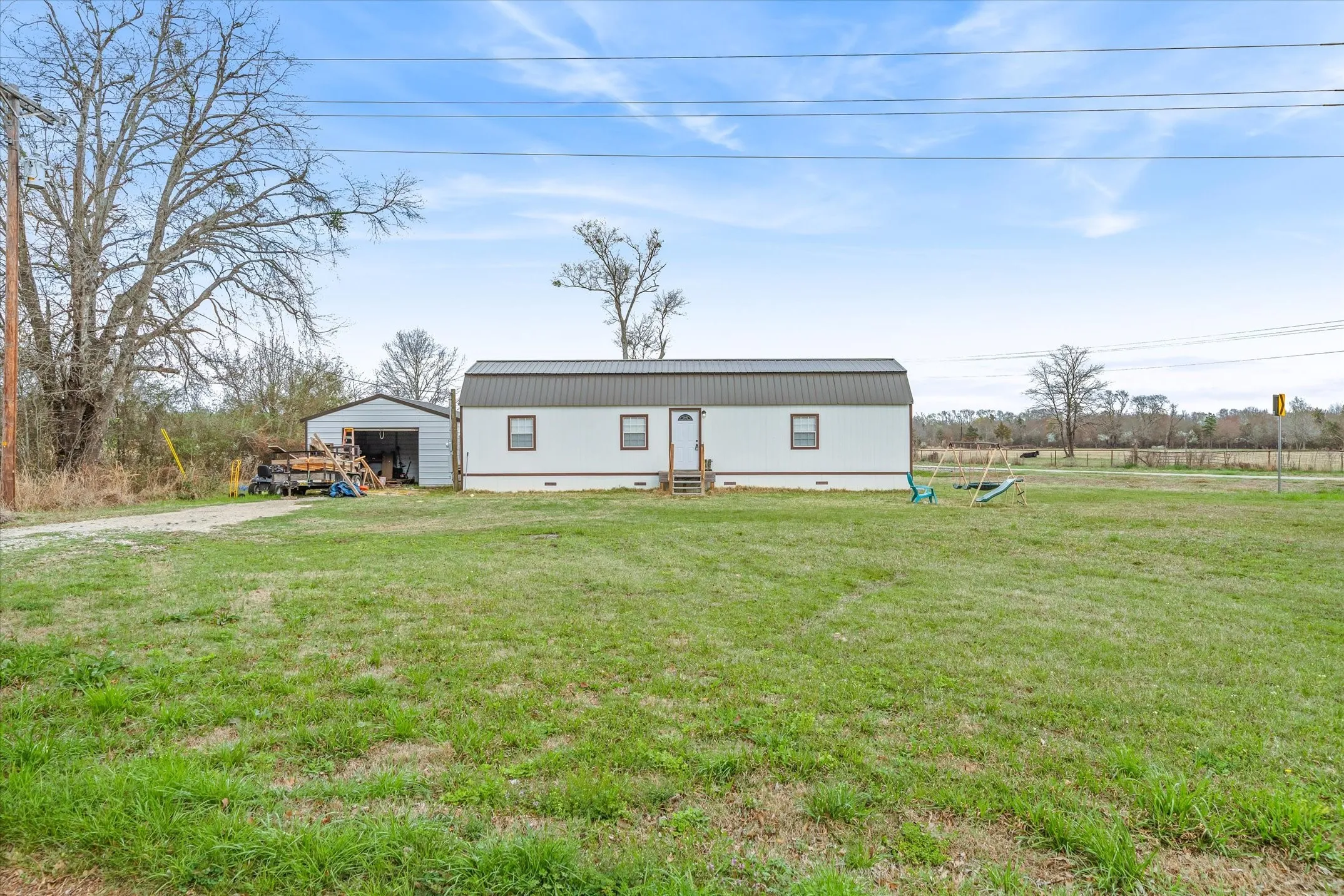 View of front of home with a front lawn, an outdoor structure, a detached garage, and crawl space