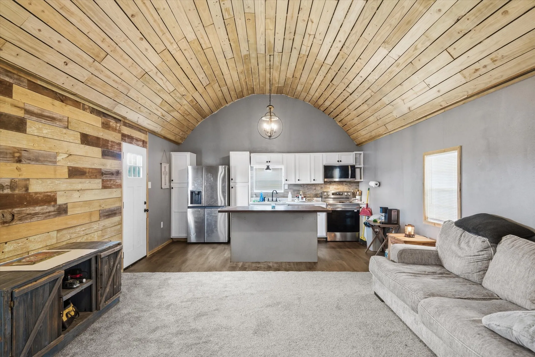 Livingroom featuring open floor plan, white cabinets, stainless steel appliances, a kitchen island, and a vaulted wooden ceiling