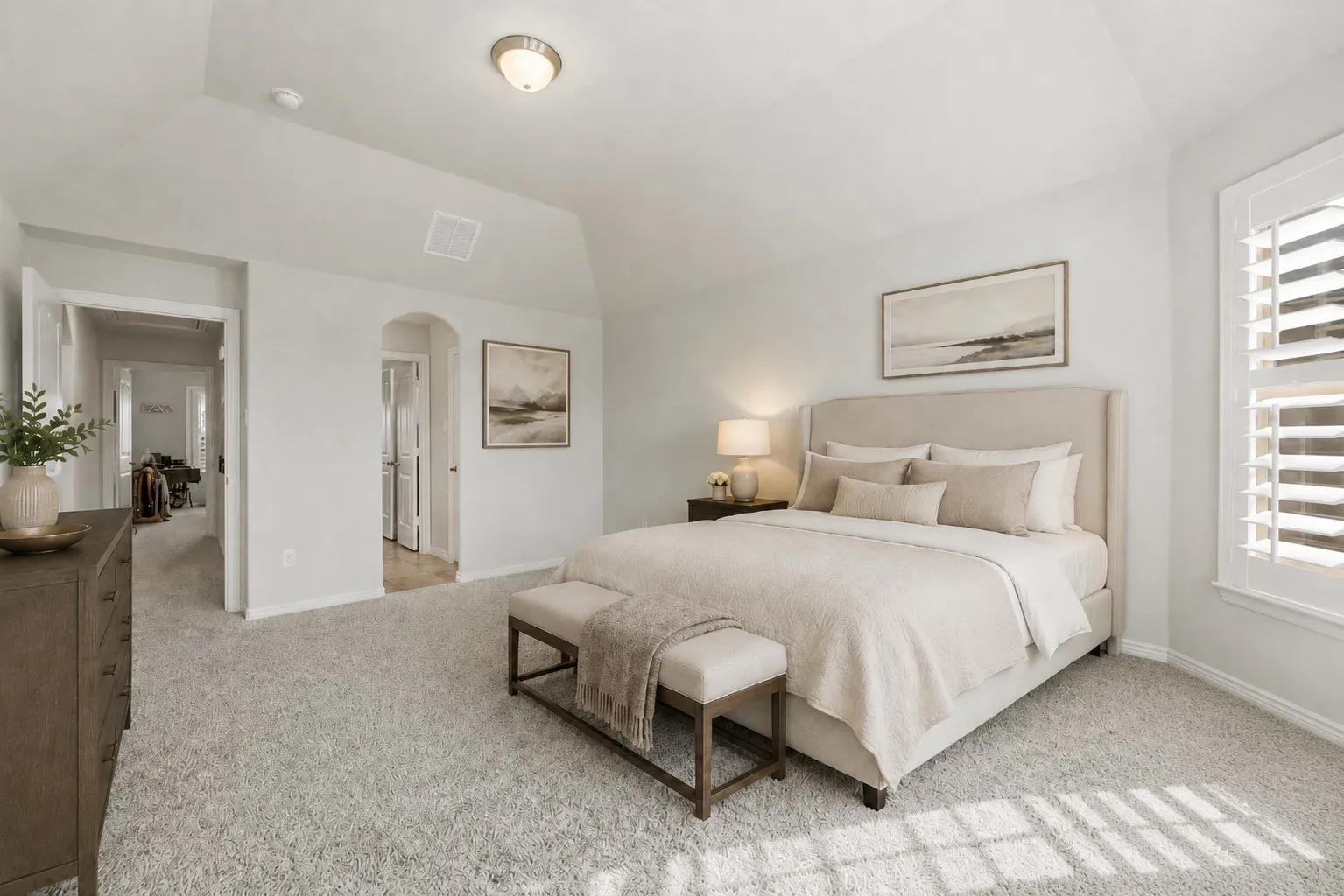 Plush carpeting, vaulted ceiling, and recessed lighting enhance this spacious bedroom
