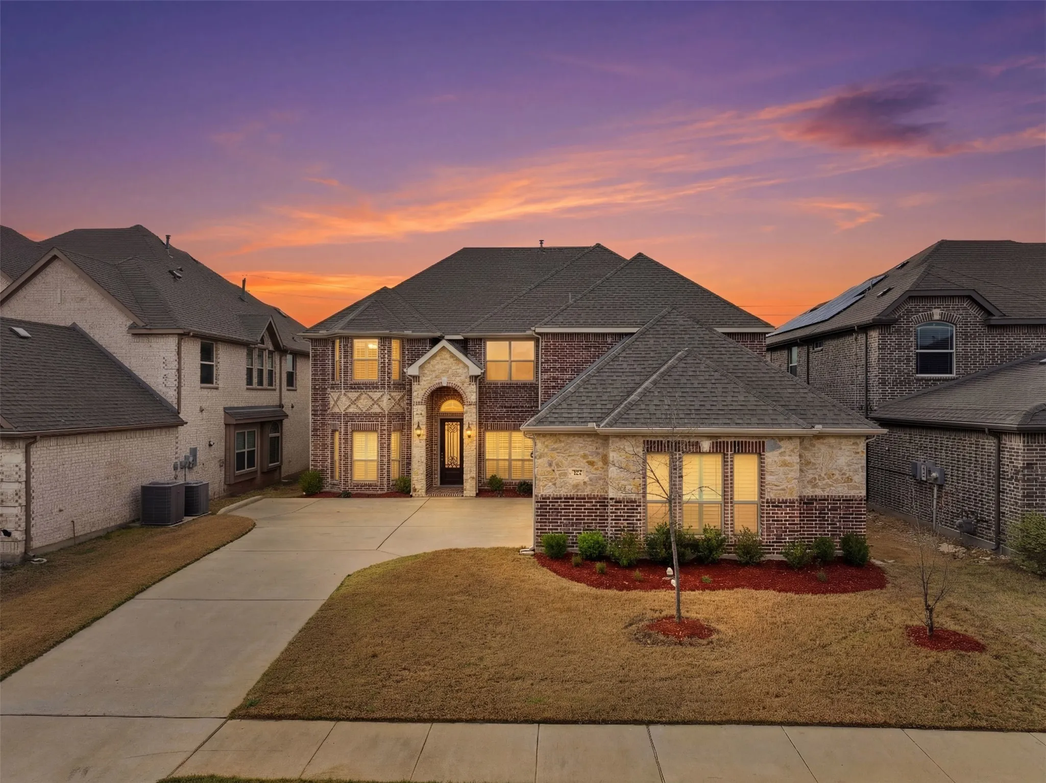 French country home with concrete driveway, brick siding, stone siding, and a shingled roof