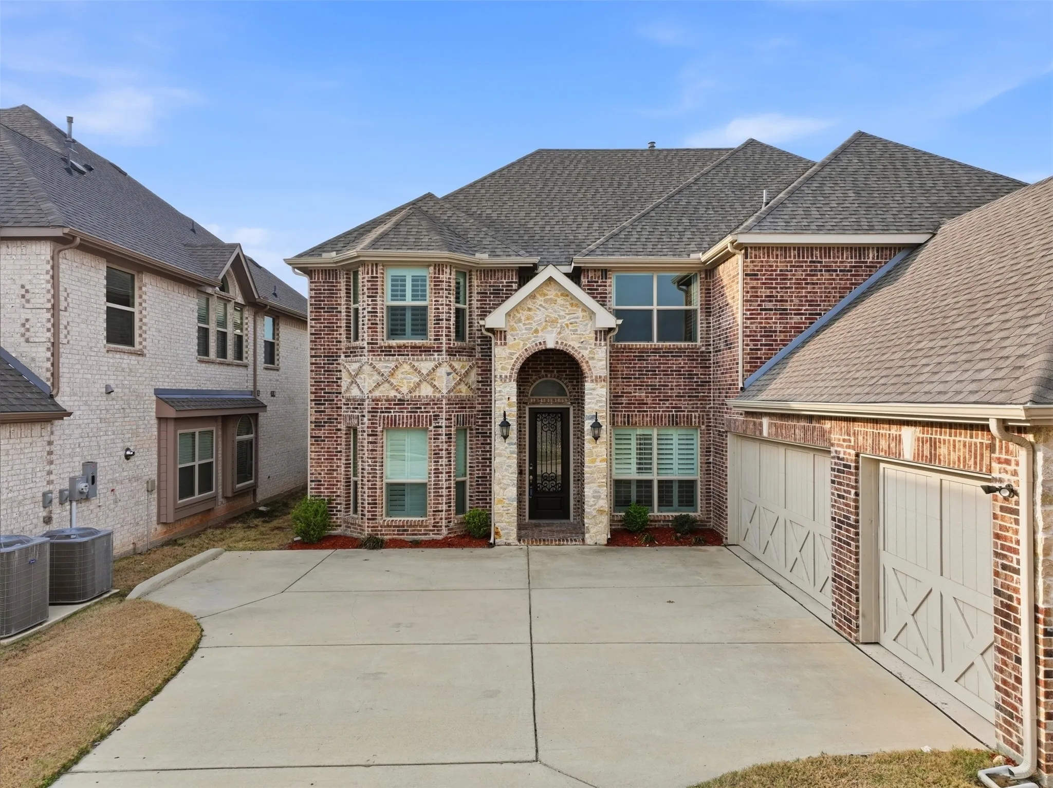 View of front of home featuring roof with shingles, brick siding, driveway, and an attached garage