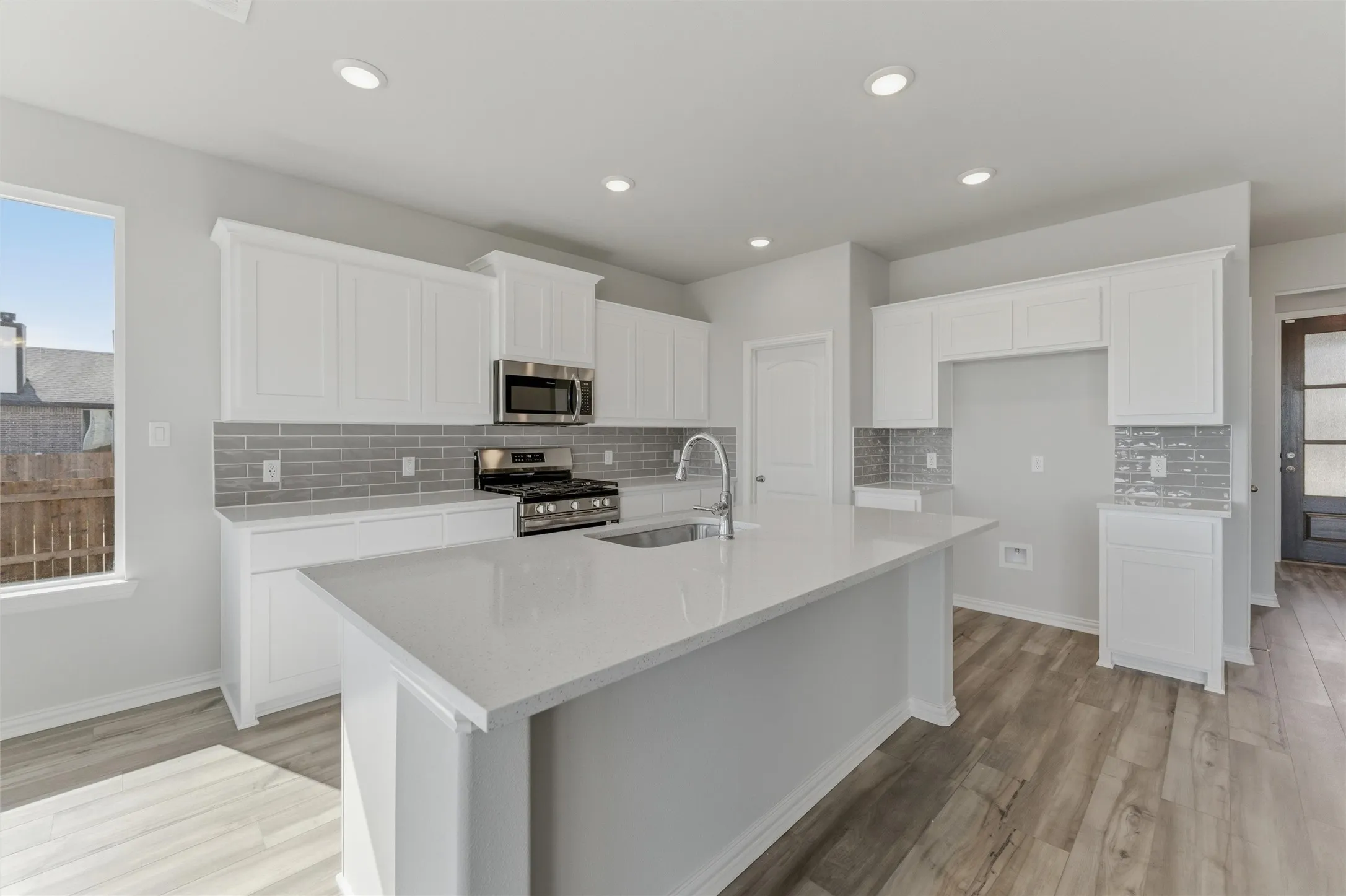 Kitchen with healthy amount of natural light, white cabinets, stainless steel appliances, tasteful backsplash, and recessed lighting
