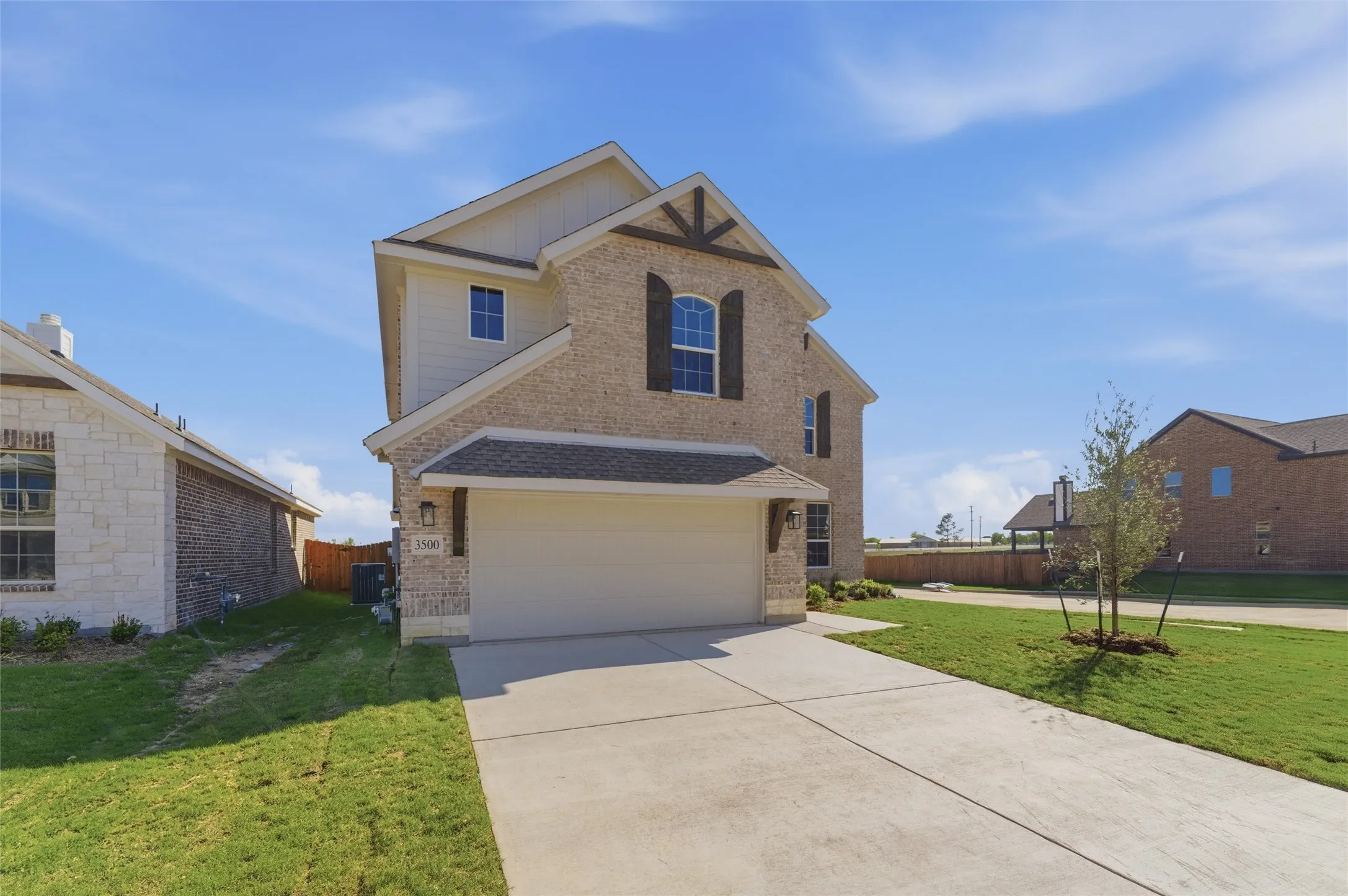 View of front of property with brick siding, driveway, and a garage