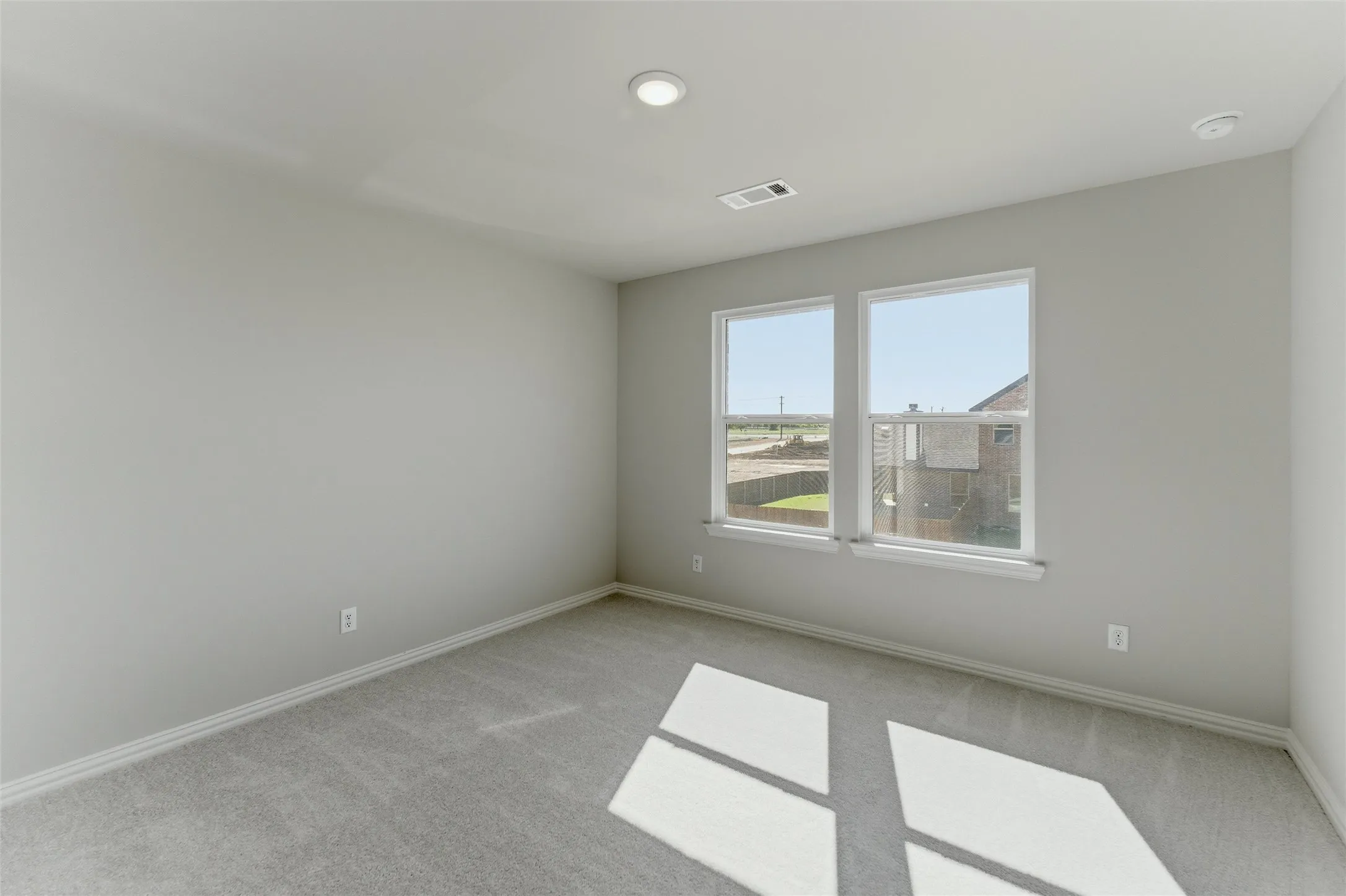 Empty room with light colored carpet and baseboards