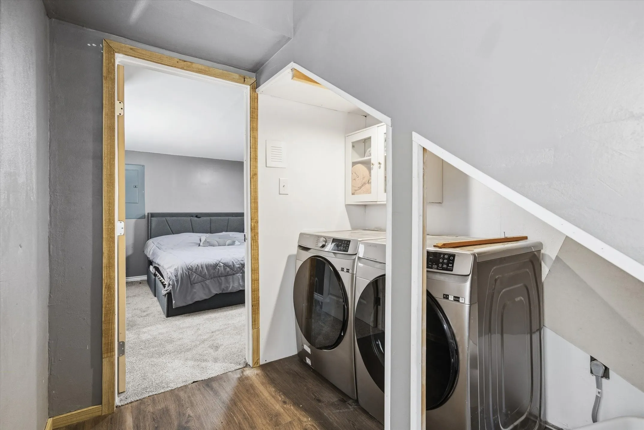 Laundry area with dark wood finished floors, washing machine and dryer, and electric panel