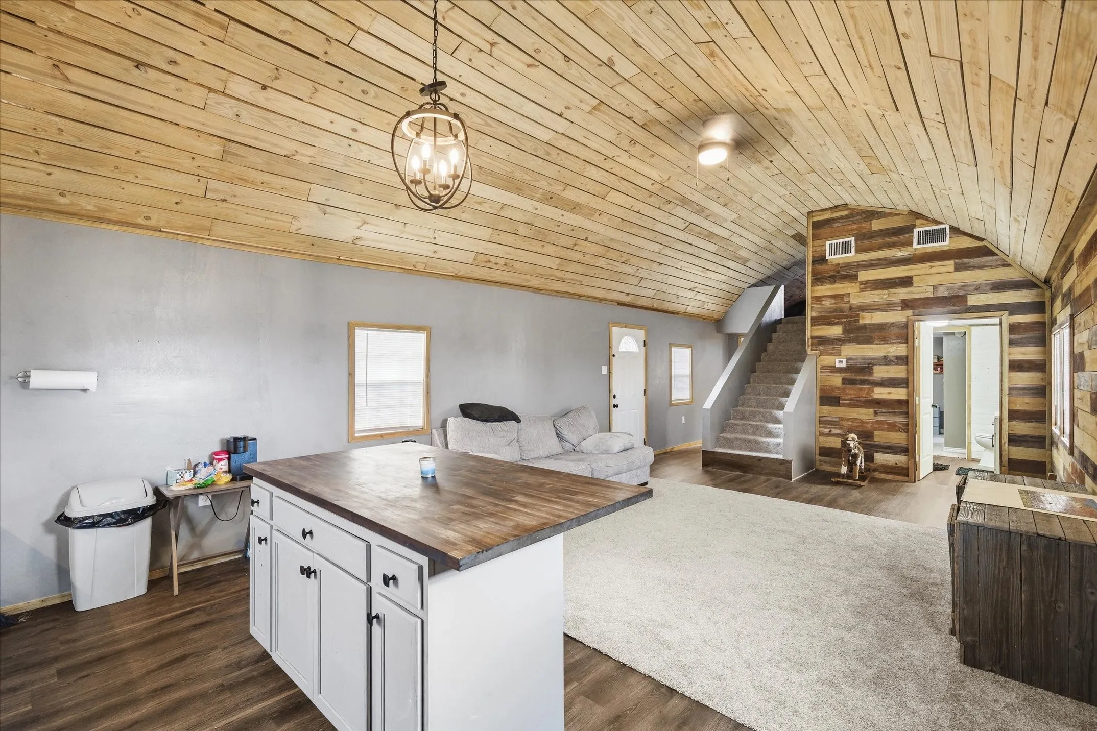 Kitchen featuring wooden walls, plenty of natural light, hanging light fixtures, wooden counters, and dark wood-style flooring