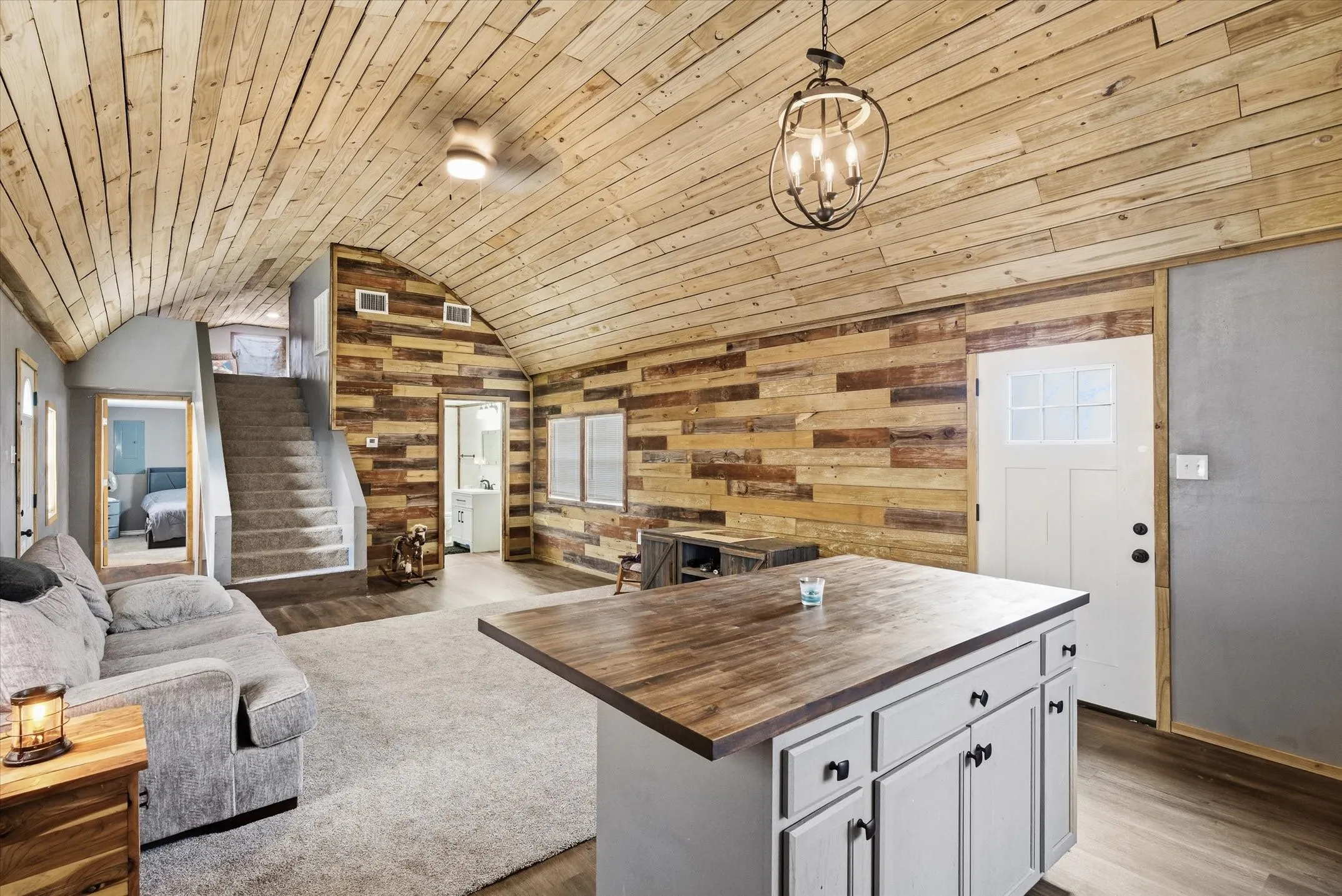 Kitchen featuring wood counters, hanging light fixtures, wooden walls, a kitchen island, and open floor plan