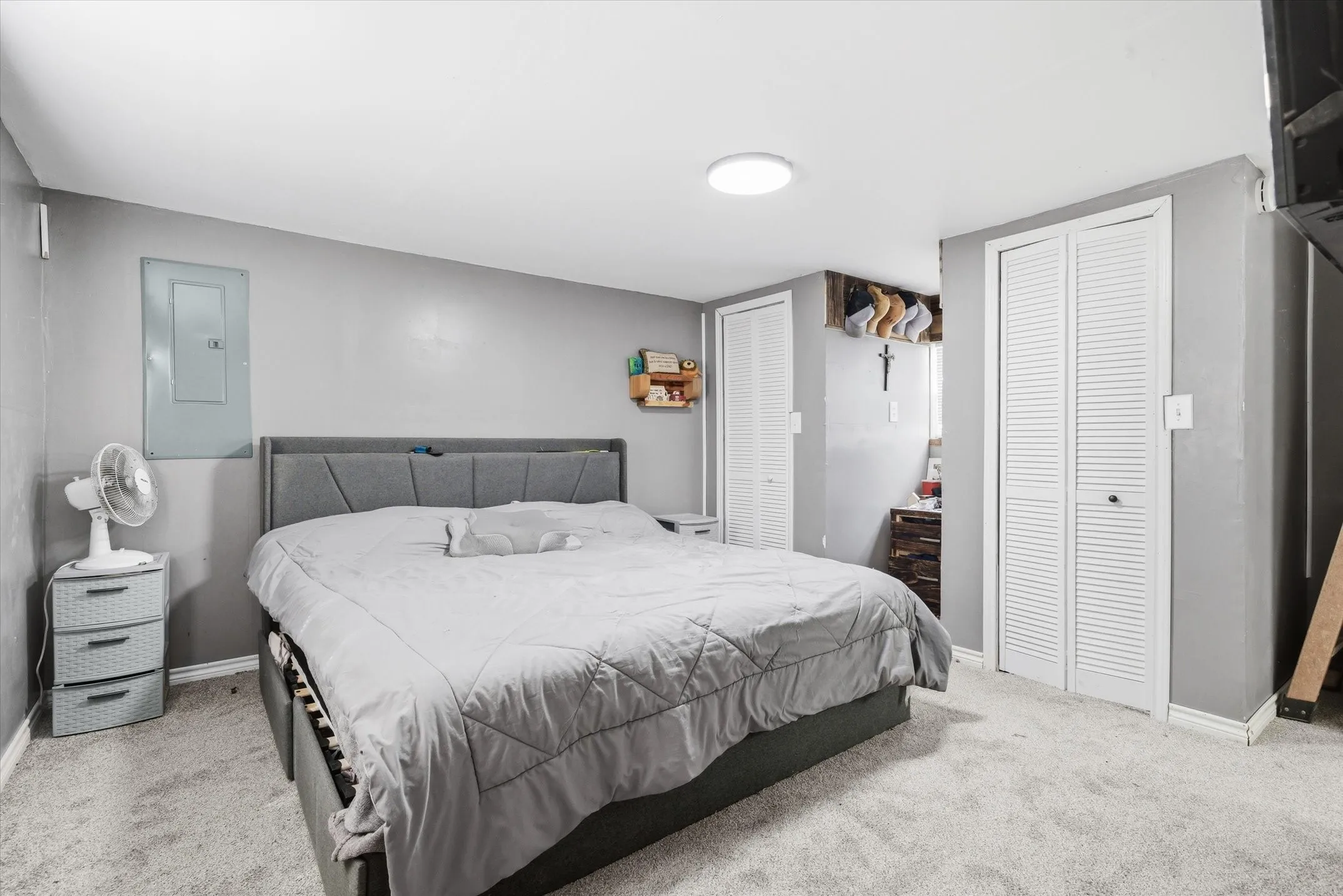 Bedroom with multiple closets, electric panel, and carpet flooring