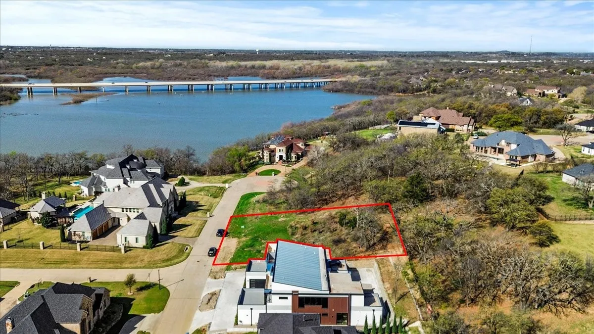 Aerial view of residential area with property boundaries highlighted, a notable bridge, and a large body of water