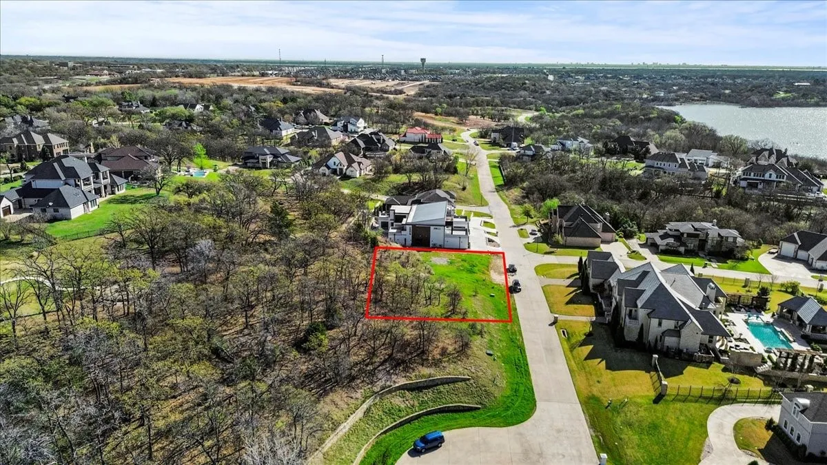 Aerial perspective of suburban area with property boundaries highlighted and a large body of water