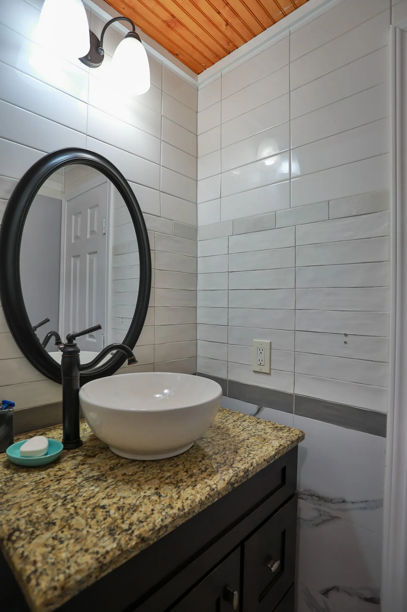 Bathroom vanity featuring a vessel sink, black faucet, and granite countertop