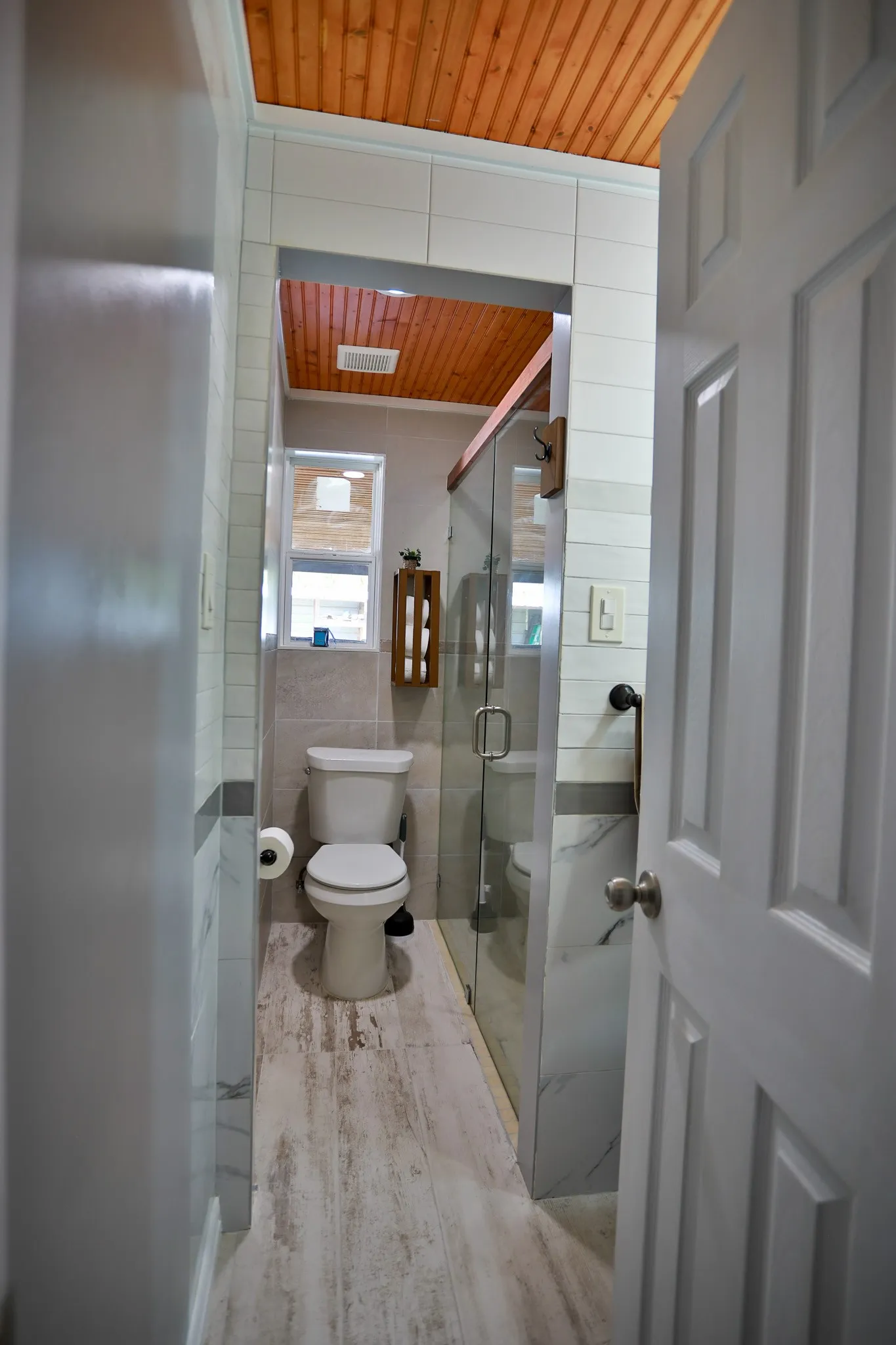 Bathroom featuring wood-finish plank flooring, a white toilet, and a glass-enclosed shower