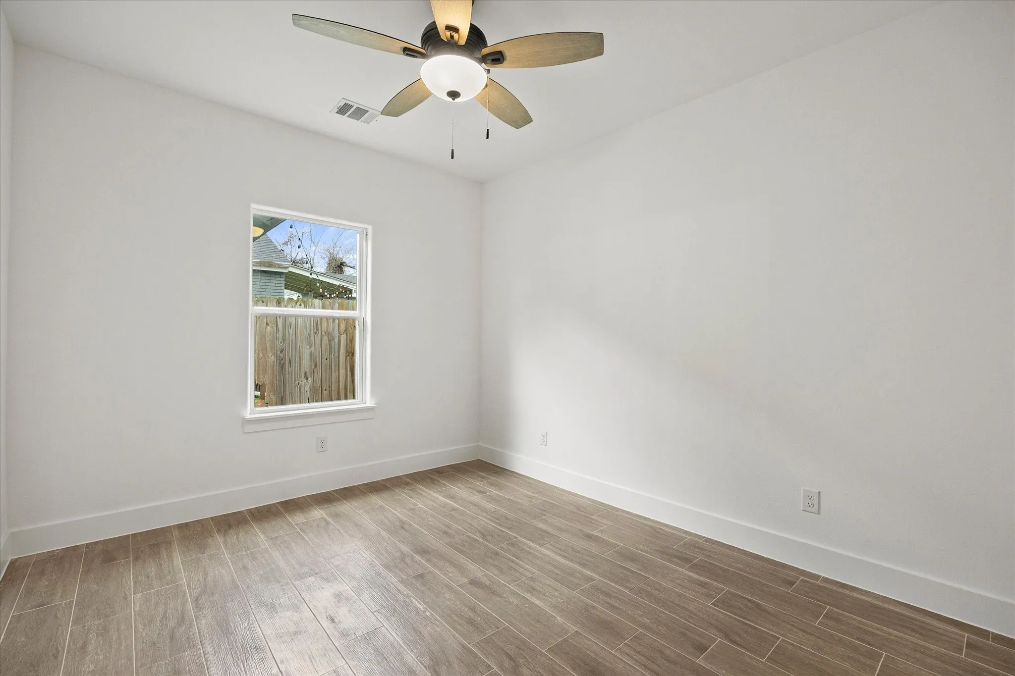 Empty room with wood tiled floors and a ceiling fan
