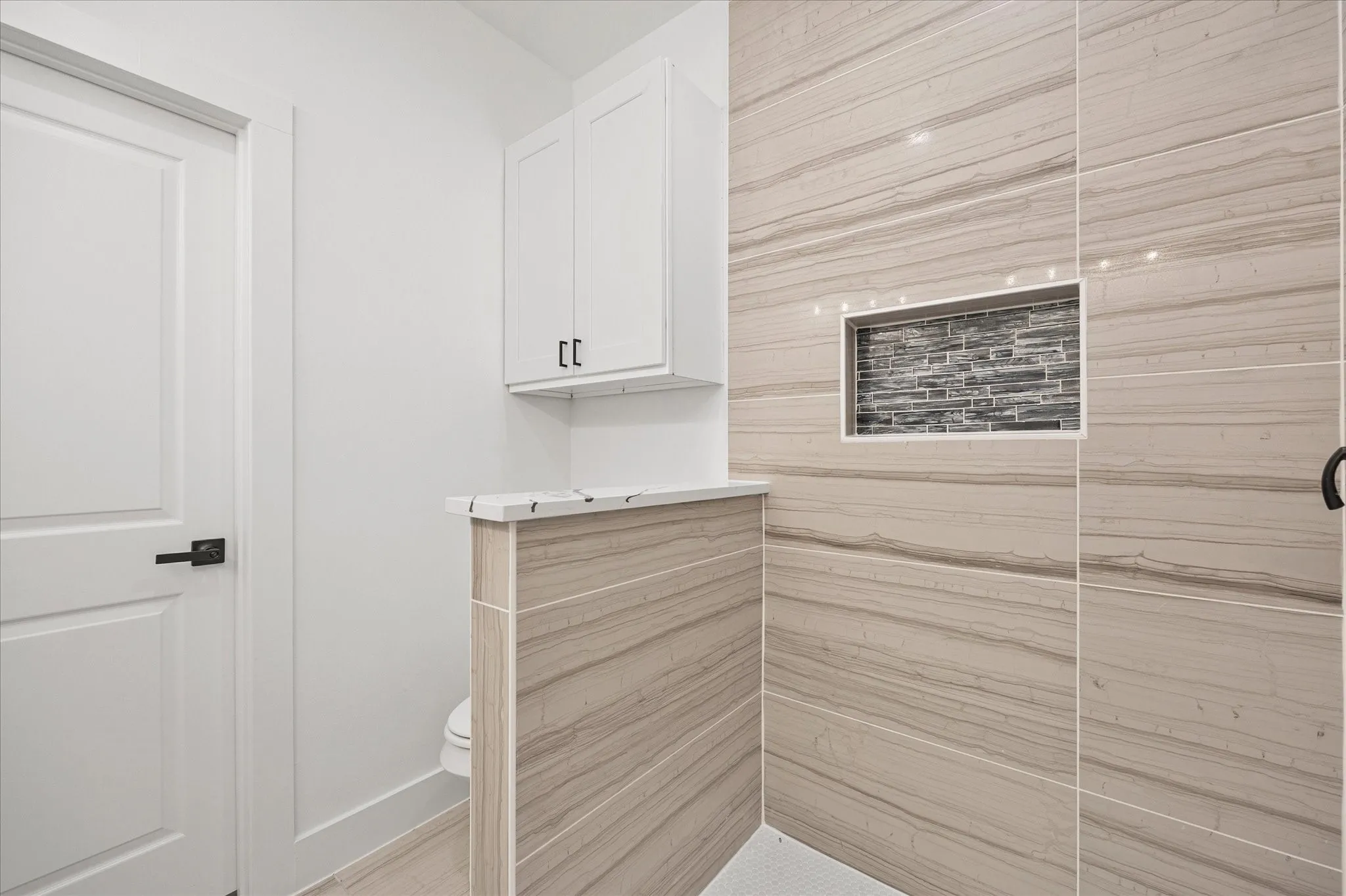Bathroom view of toilet and a tile shower