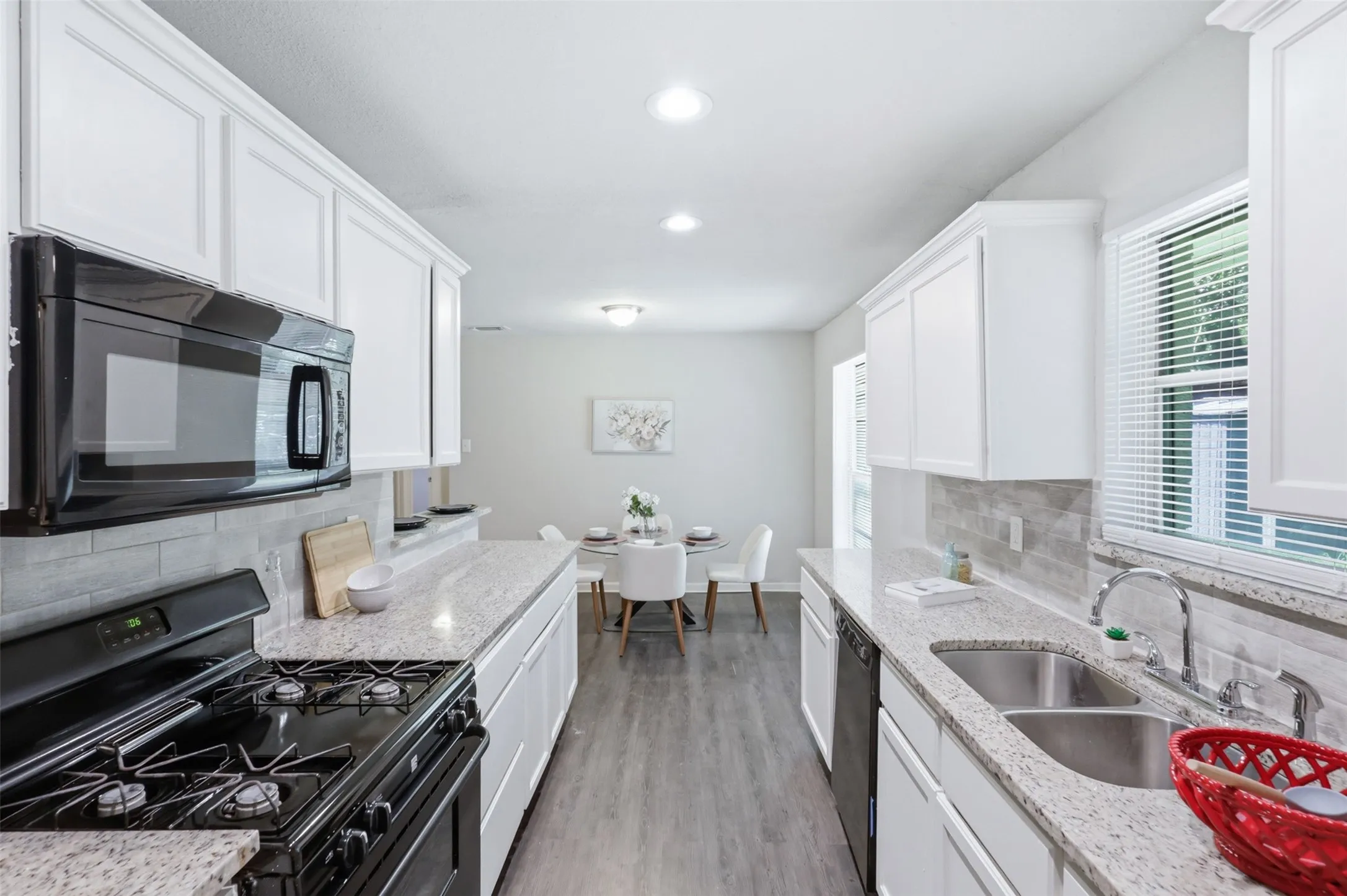Galley kitchen with granite countertops, painted cabinets and coordinating tile backsplash.