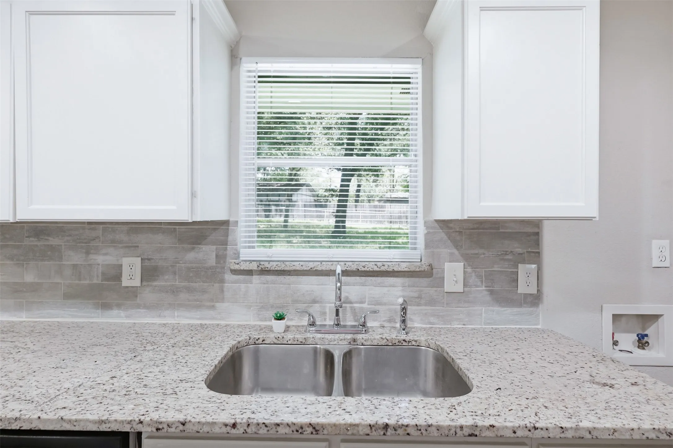 Quaint window above stainless steel sink overlooks the backyard.