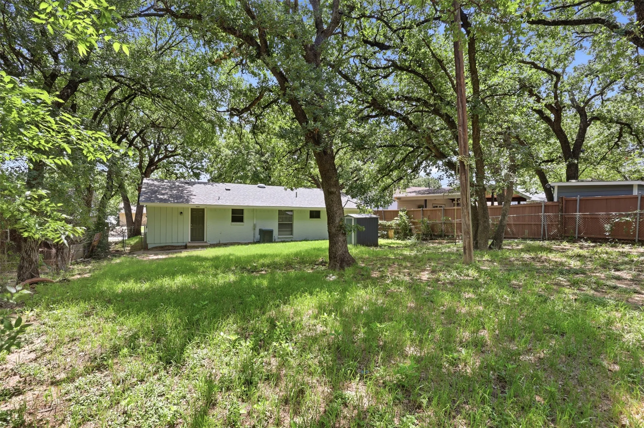 Large backyard with mature trees and plenty of space for a garden or play structure.