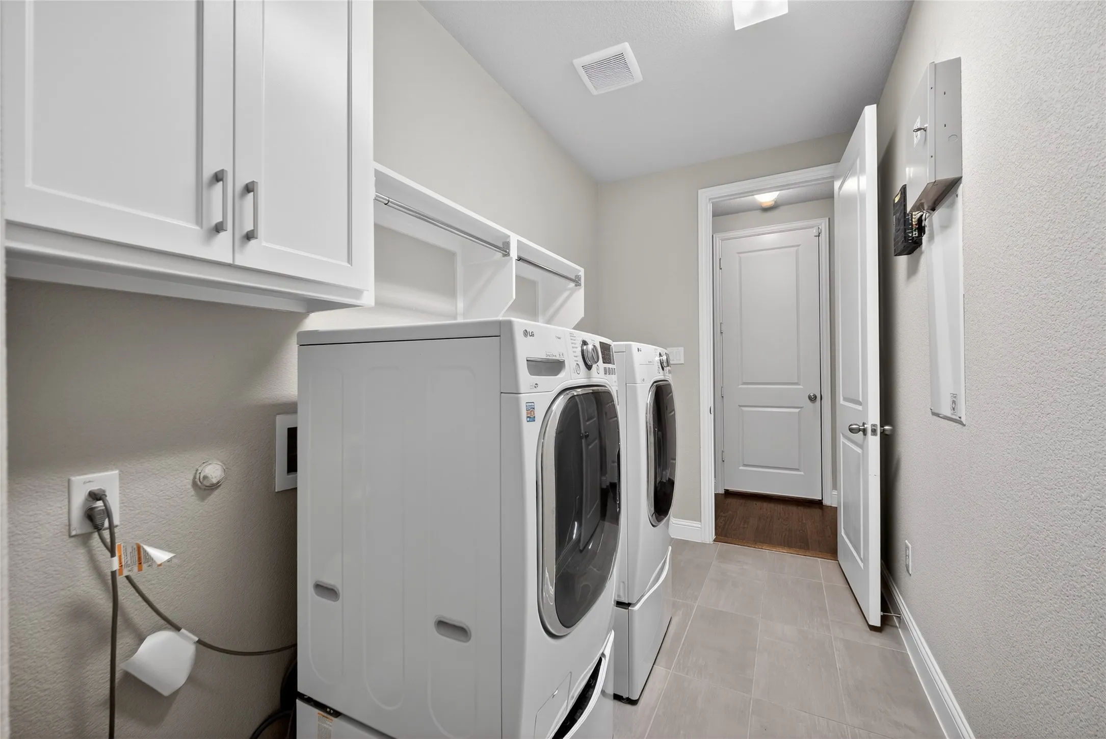Laundry room featuring a textured wall, cabinet space, independent washer and dryer, and light tile patterned floors