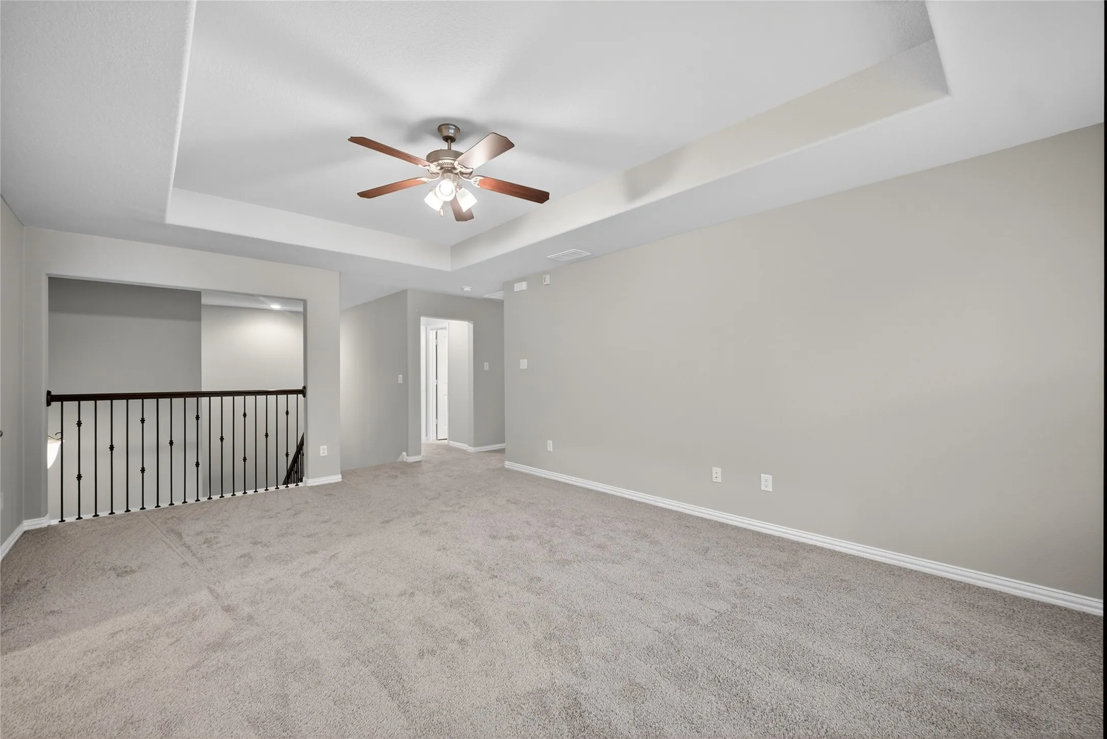 Spare room featuring a tray ceiling, carpet, and ceiling fan