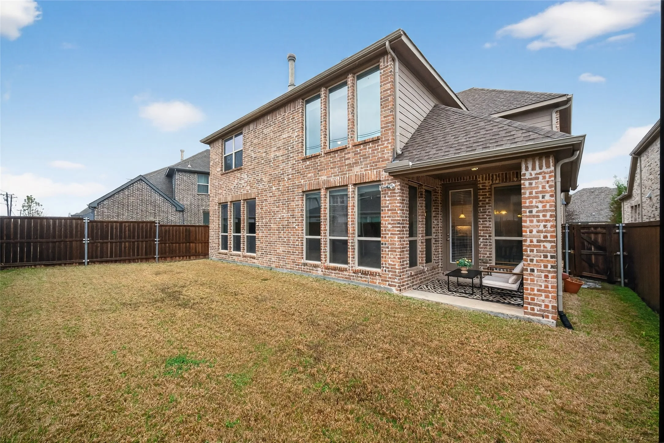 Back of property featuring a patio area, a fenced backyard, brick siding, a shingled roof, and a gate