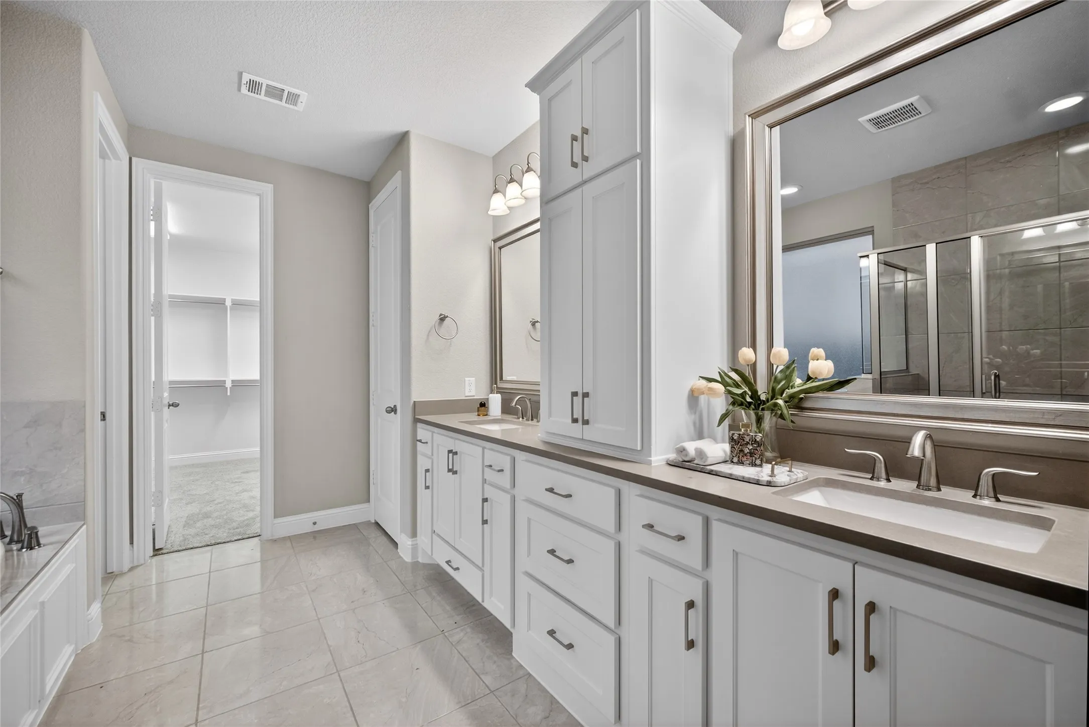 Full bath with double vanity, a shower stall, a garden tub, and a spacious closet