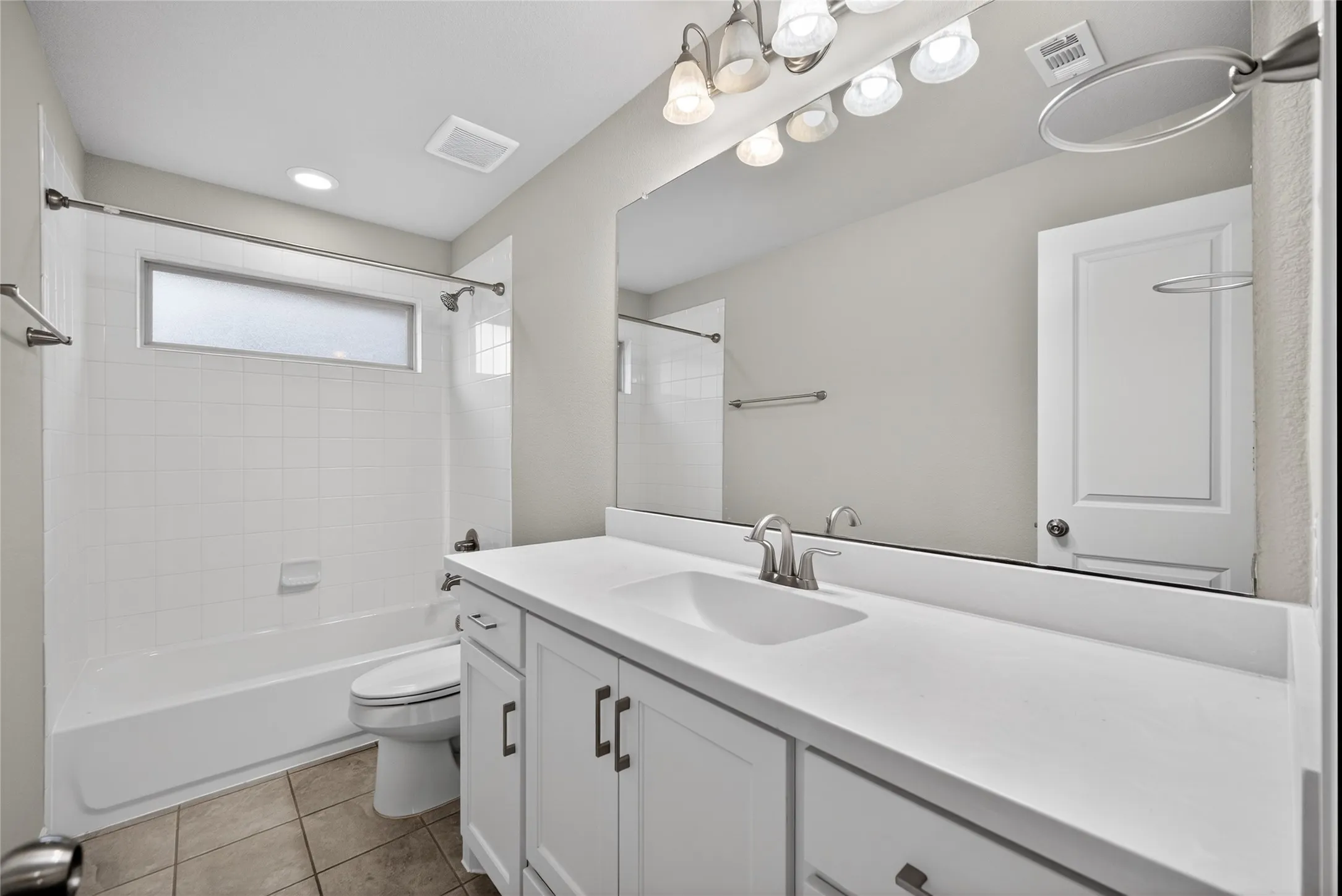 Bathroom featuring vanity, shower / bath combination, and light tile patterned floors