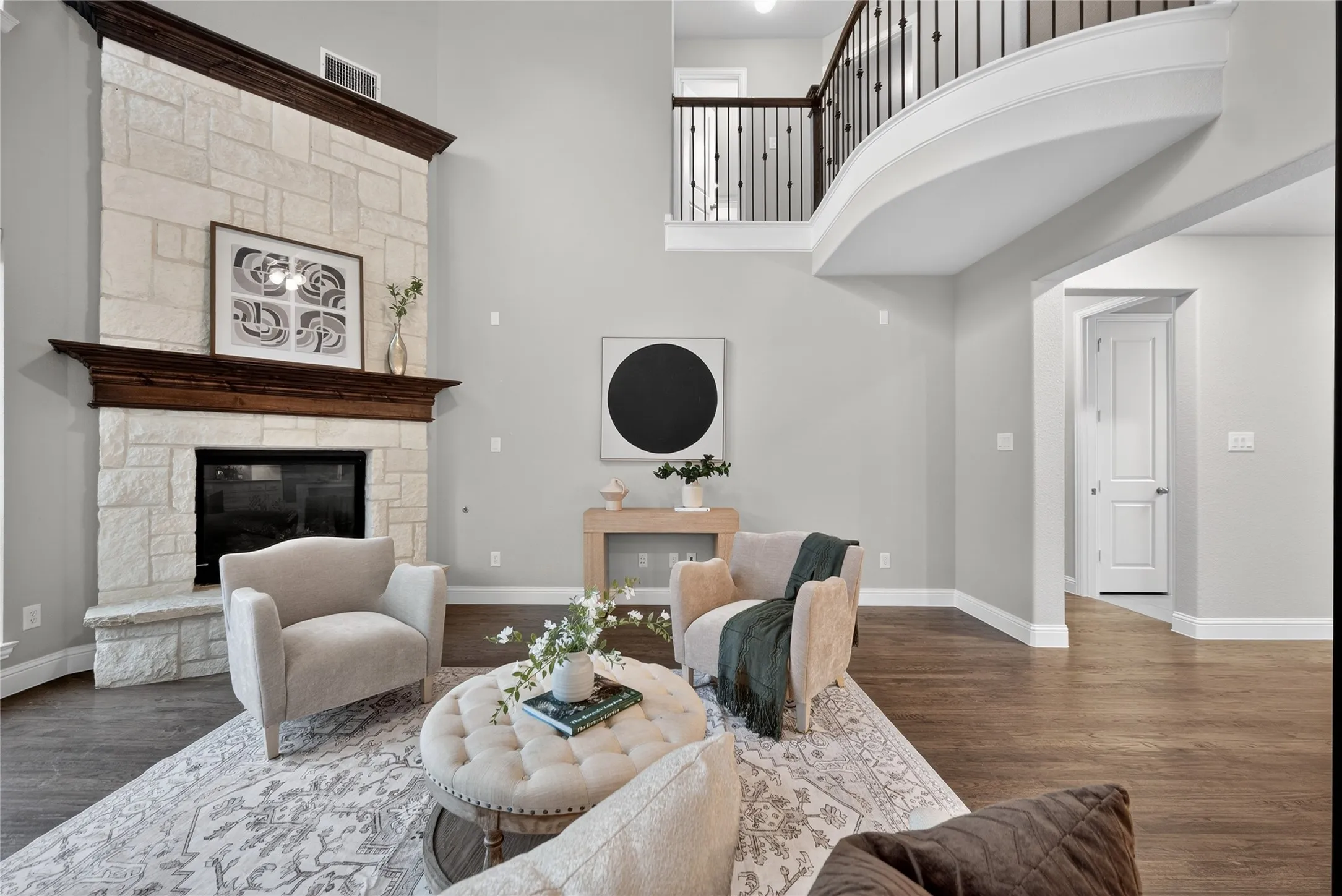 Living area featuring a stone fireplace, wood finished floors, and a high ceiling