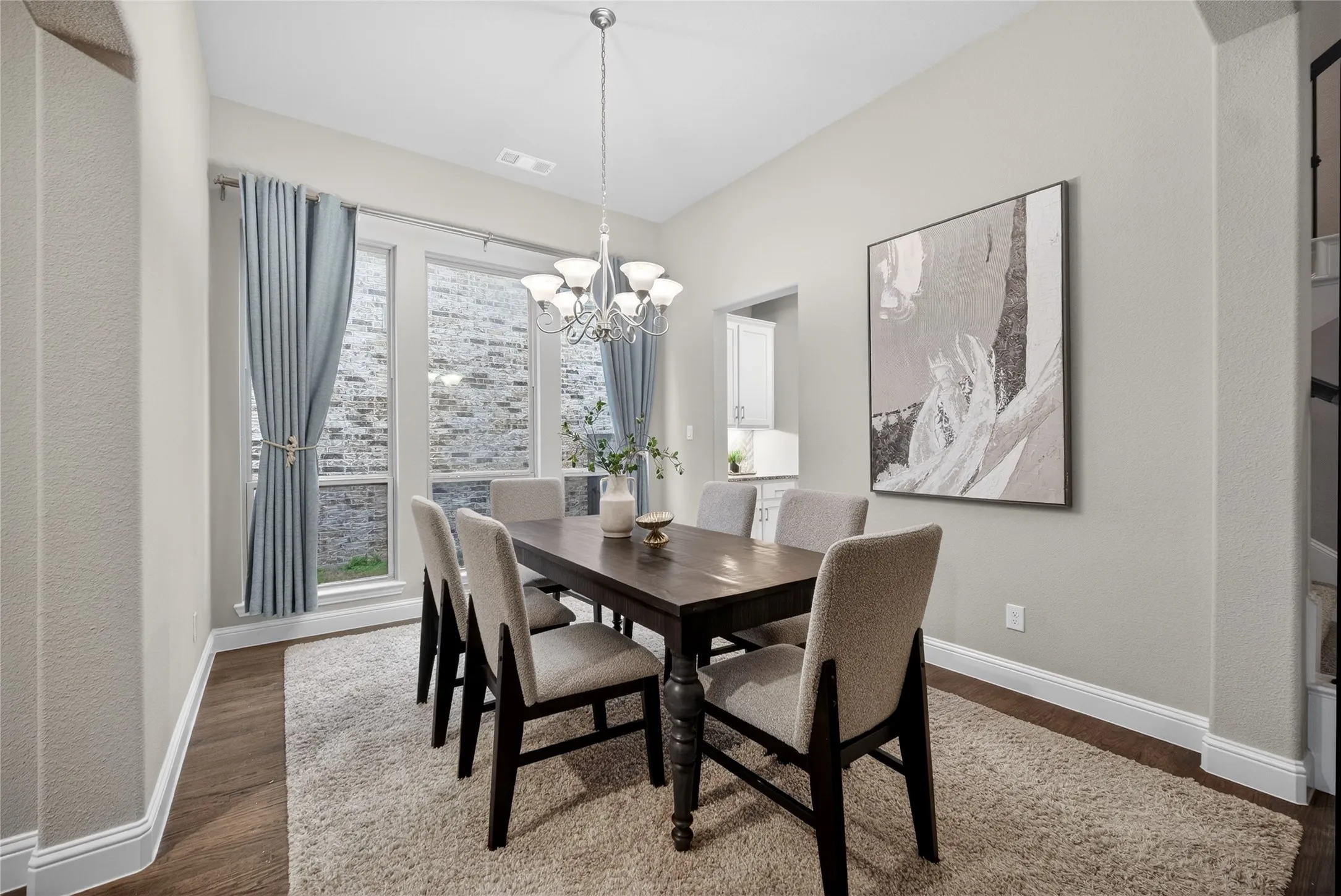 Dining room with dark wood-style floors and hanging lights