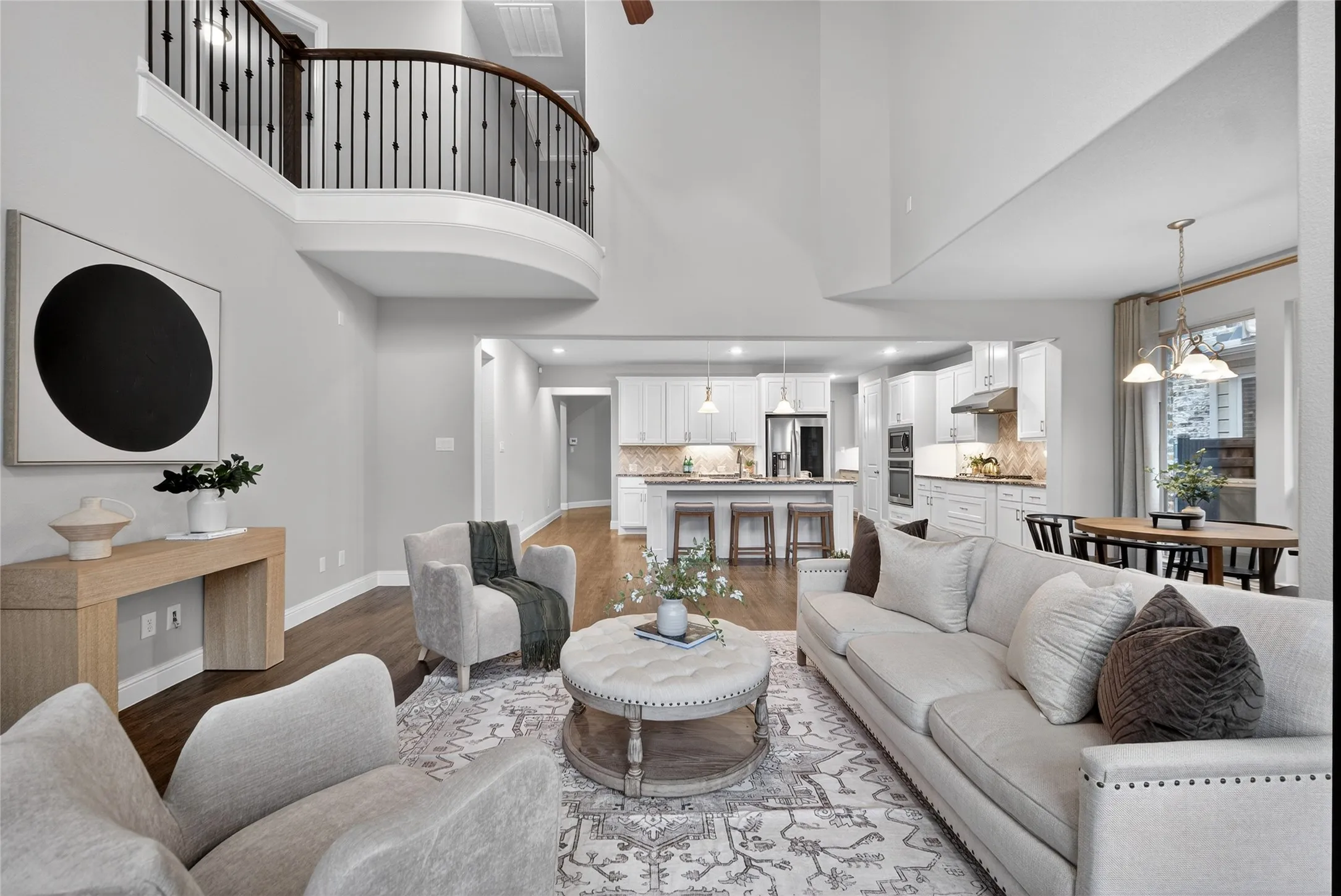 Living area with a high ceiling, wood finished floors, ceiling fan, and hanging lights