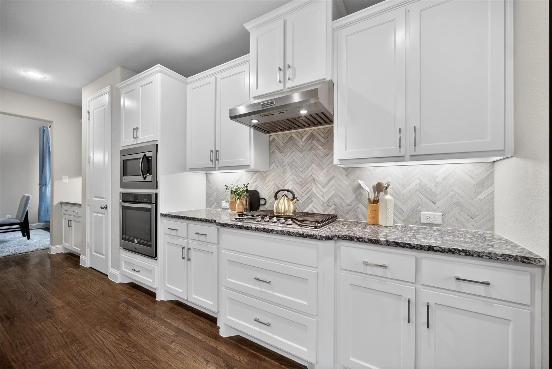 Kitchen featuring light stone counters, white cabinetry, stainless steel appliances, dark wood-style flooring, and recessed lighting