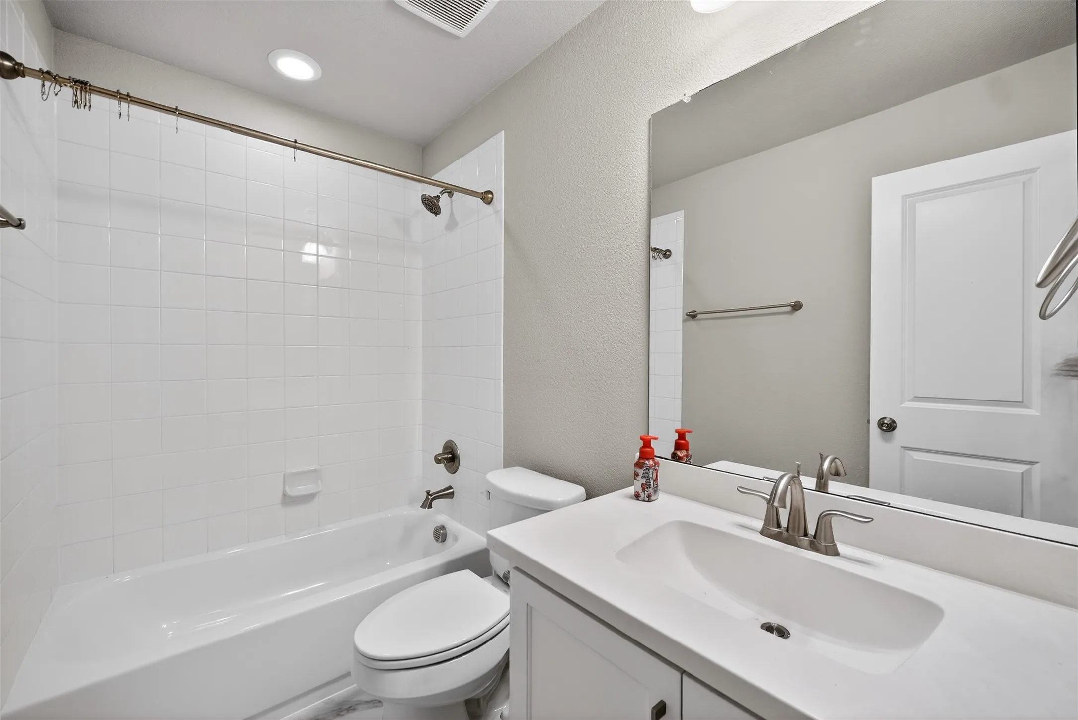 Full bathroom featuring vanity, shower / washtub combination, a textured wall, and recessed lighting
