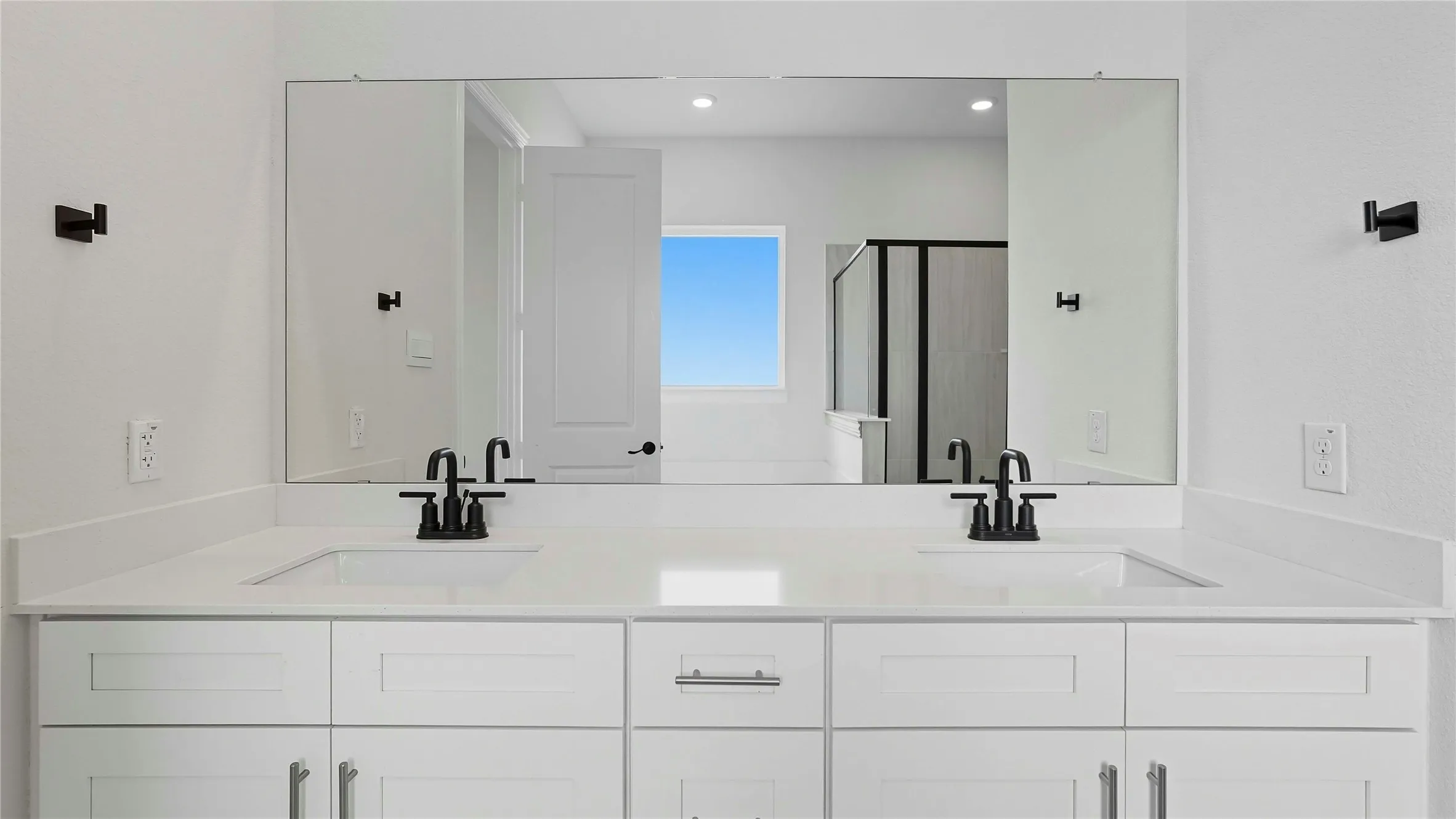 Bathroom with a shower stall, double vanity, and recessed lighting