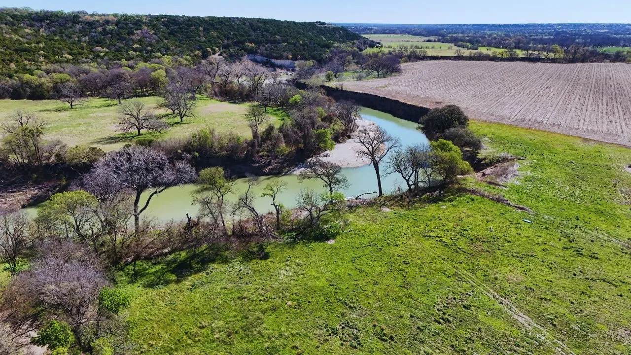 Aerial view of sparsely populated area featuring large plots for crops and a large body of water