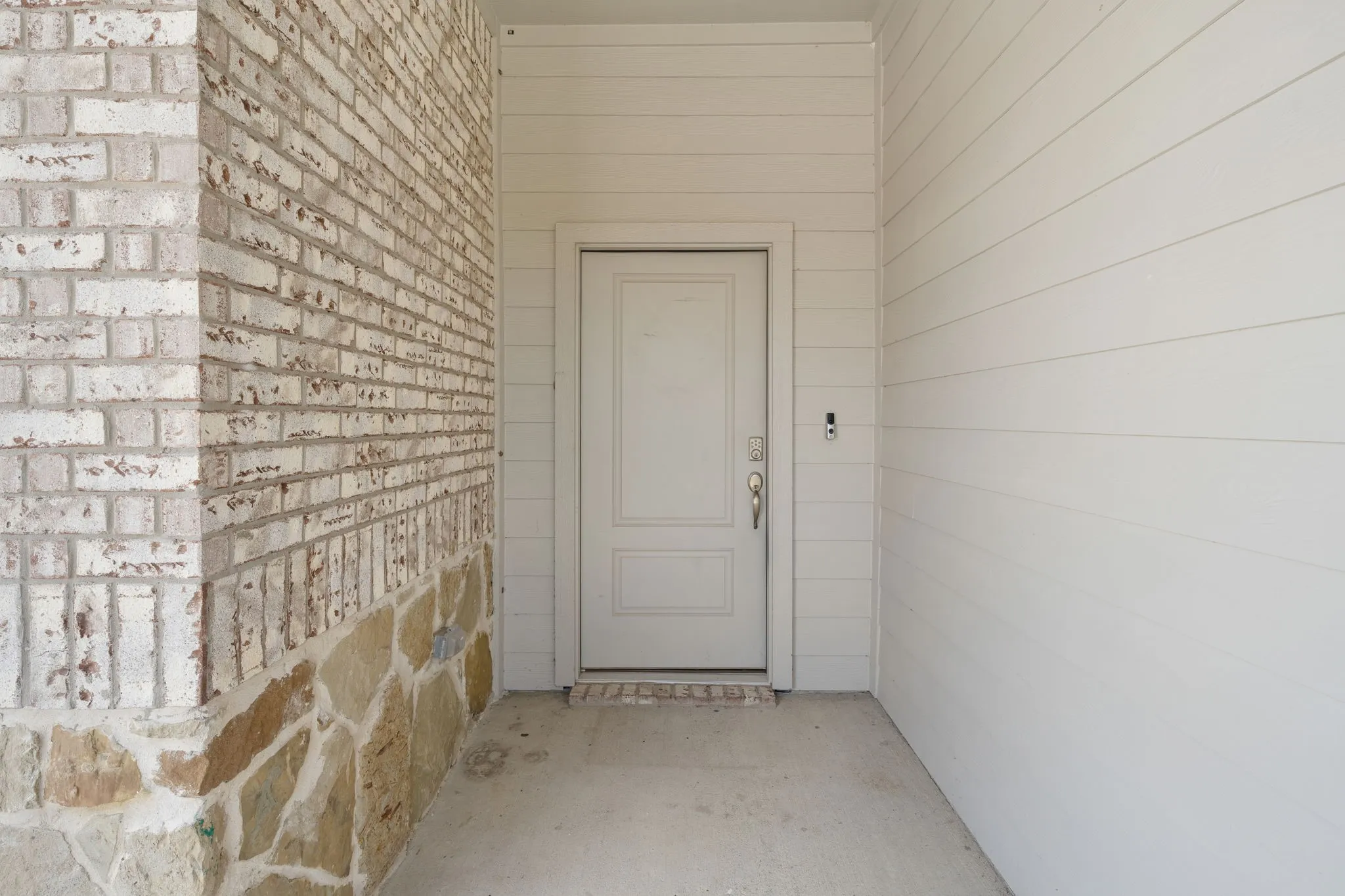 Front entry featuring a paneled door with a brushed nickel handle, surrounded by horizontal siding