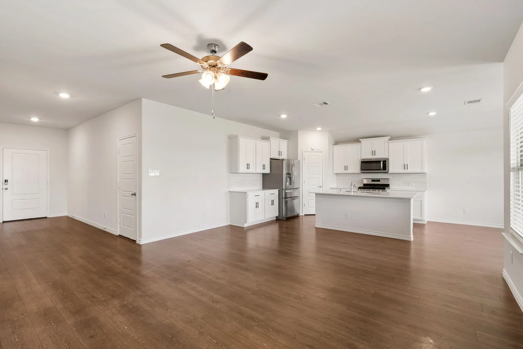 Open-concept living area with wood-finish flooring, recessed lighting, and a ceiling fan